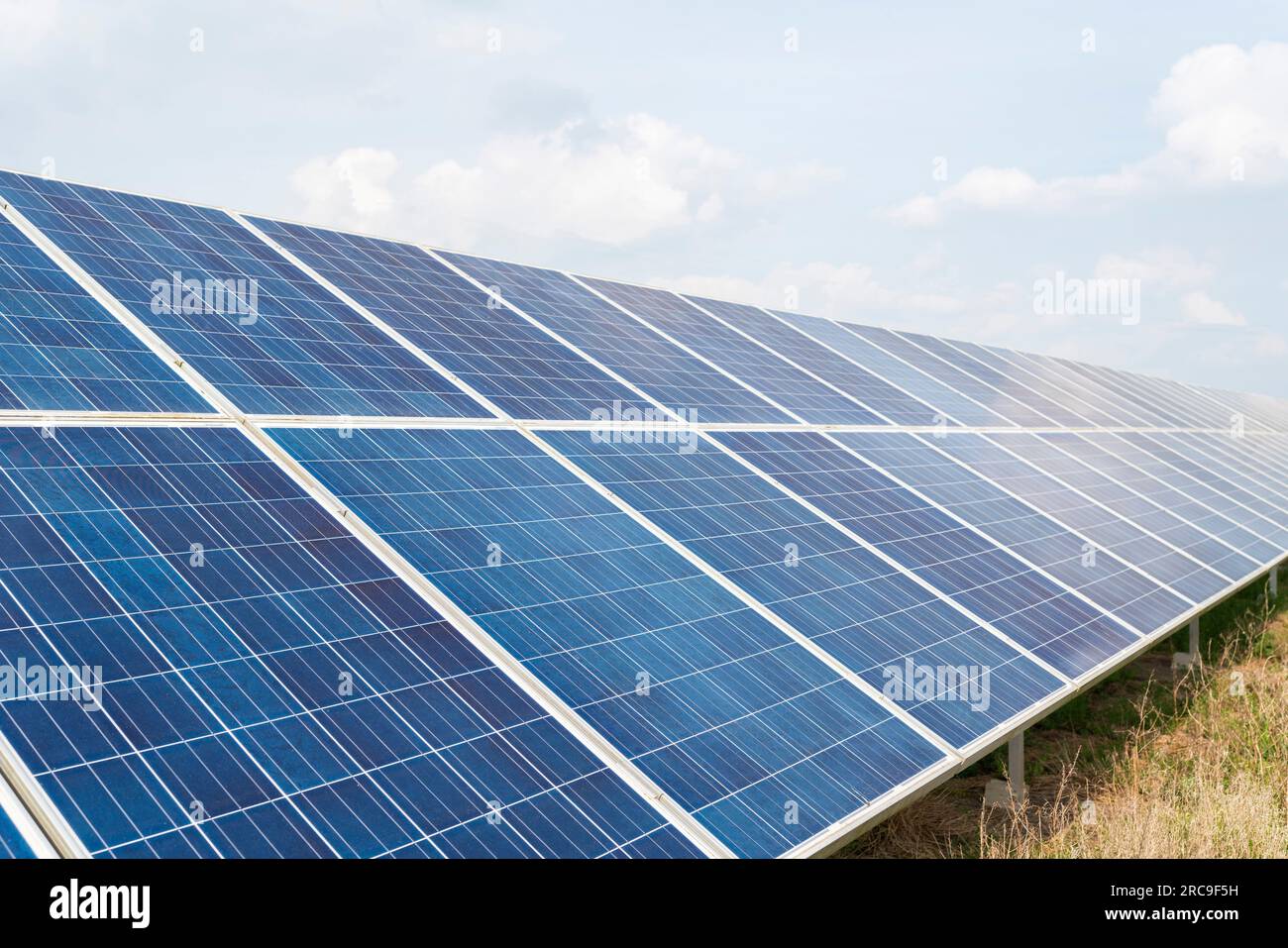 A bank of large solar panels as part of a solar farm on farm land in