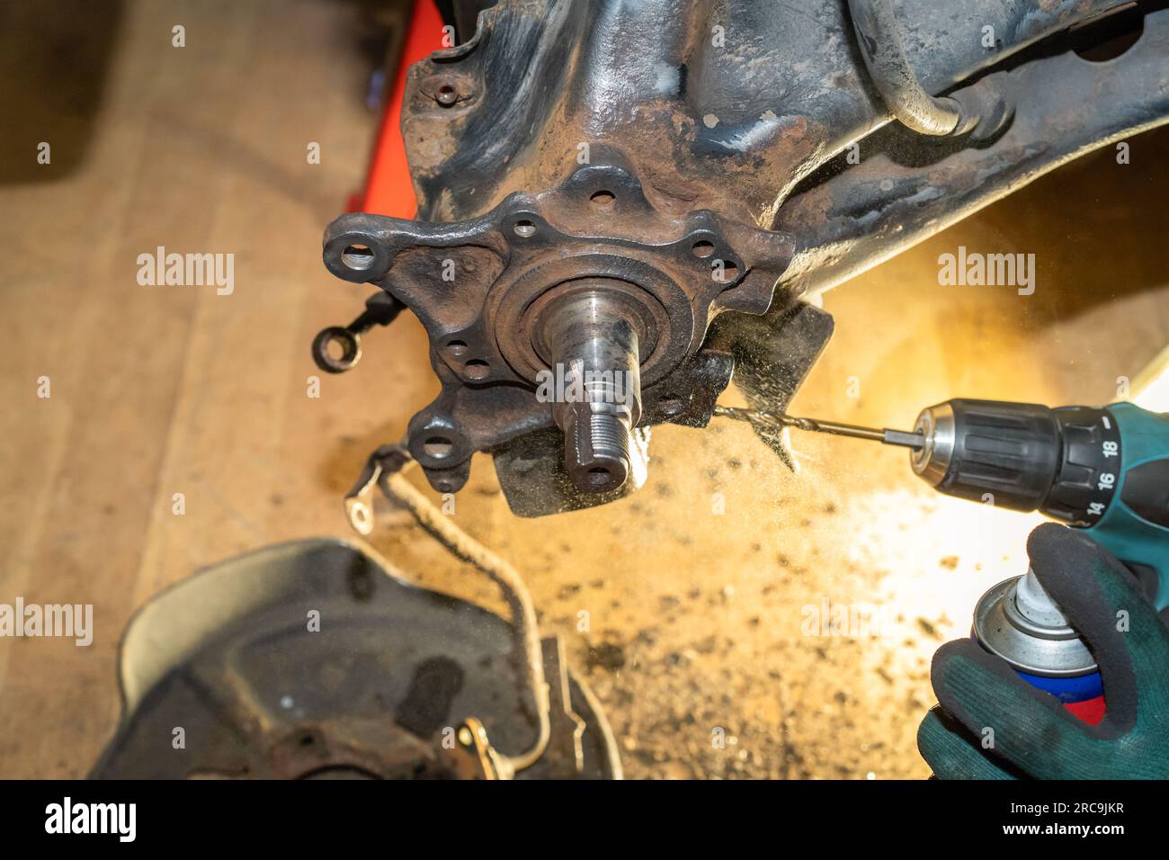 Car mechanic repair wheel hub bearing. In the process of tapping and cooling. Yellow light in