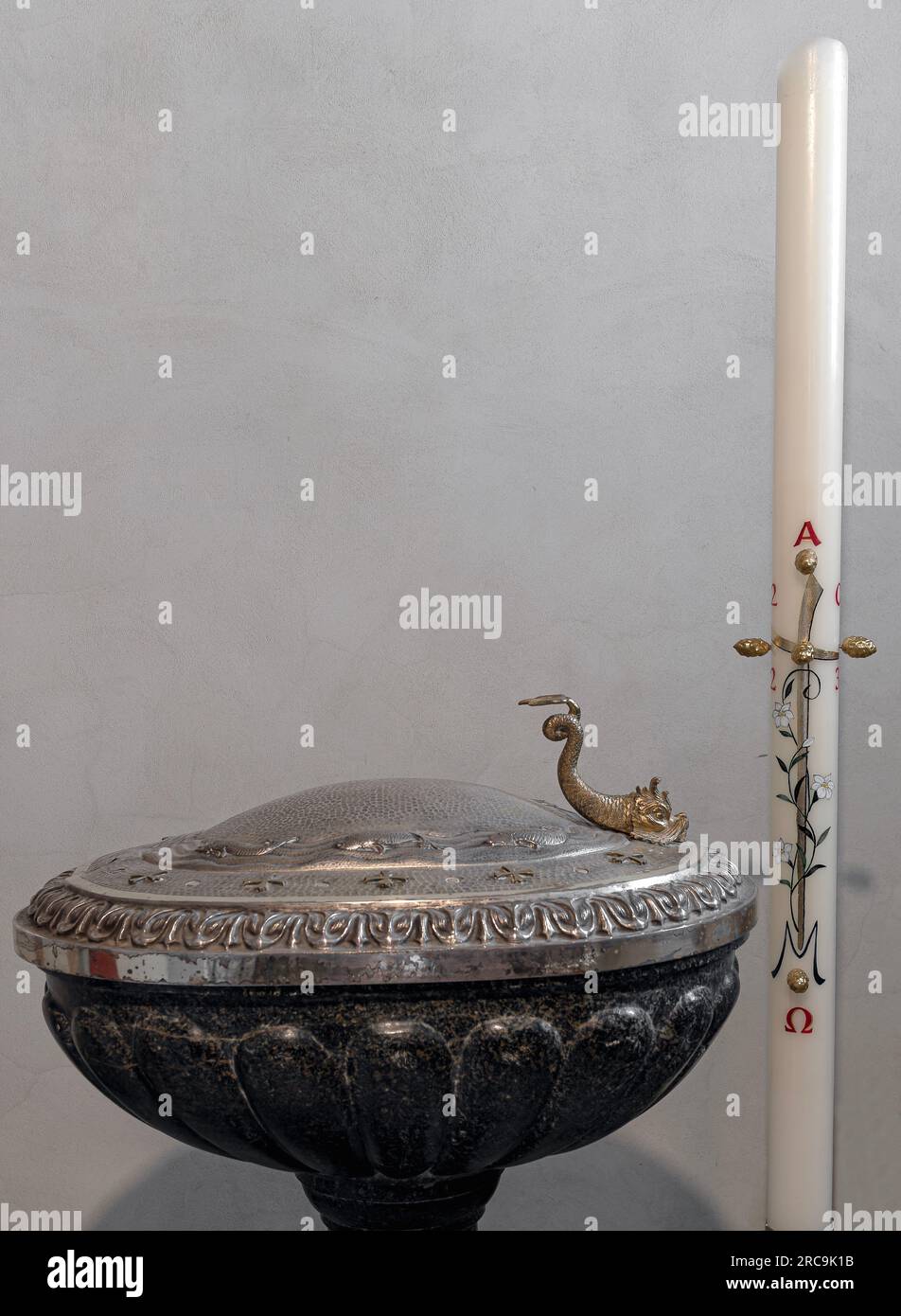 An ancient stone baptistery with a valuable artistic lid and Easter candle Stock Photo