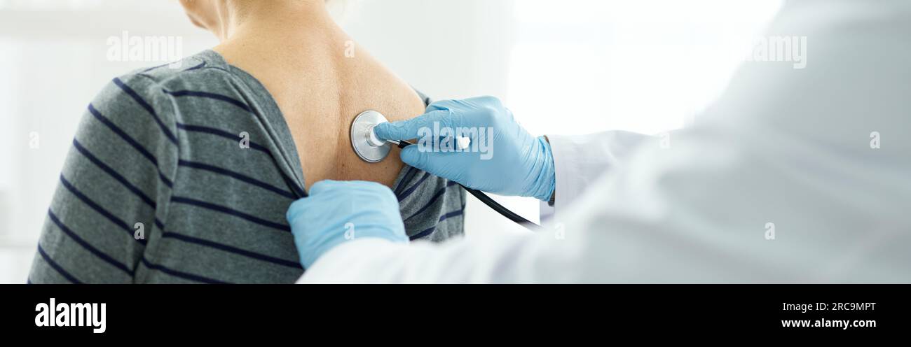 Doctor examining female patient with stethoscope in clinic Stock Photo ...