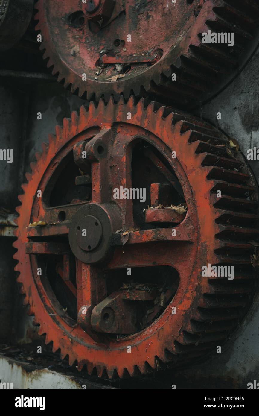 Close up of the red gear of an old defunct sheet metal working machine. Iron and steel production. Industrial history machine. Stock Photo