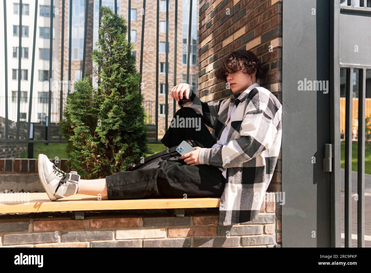 young man sits relaxed on a city bench Stock Photo