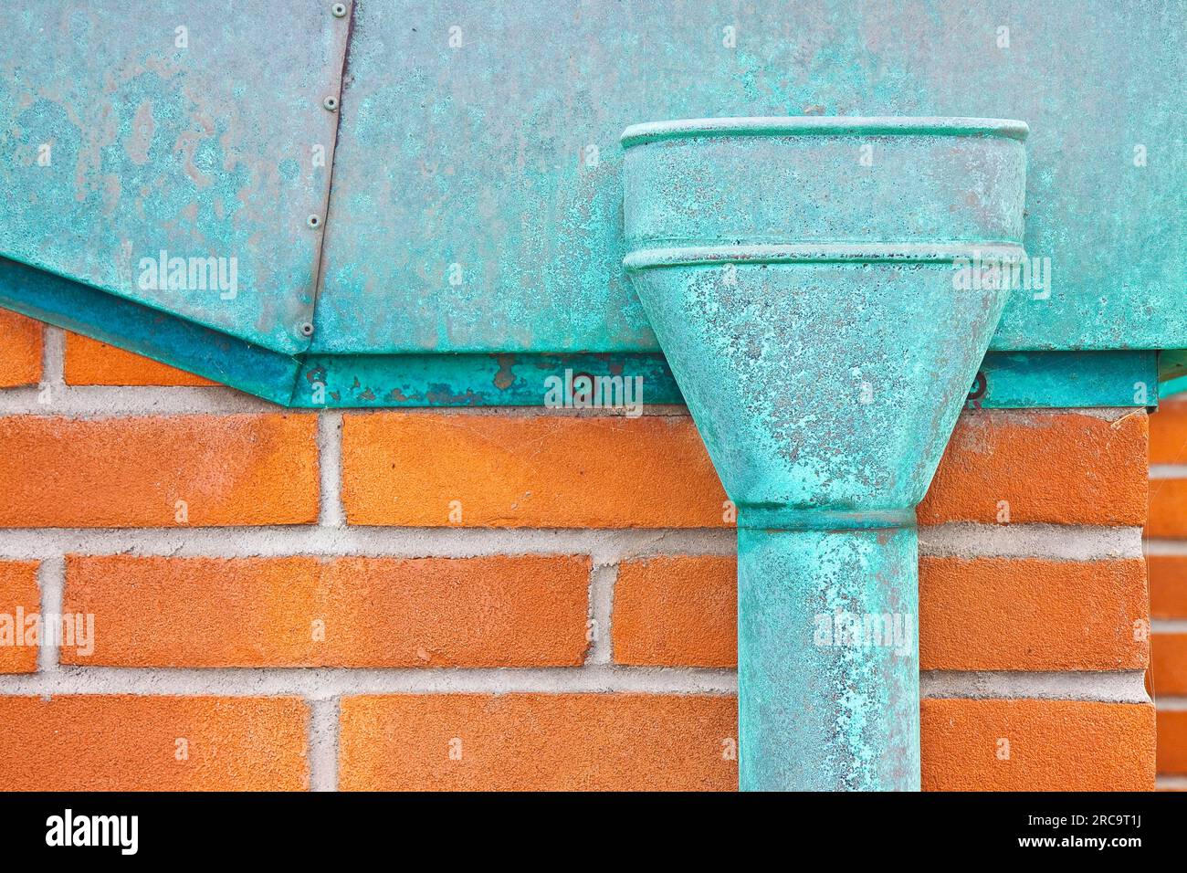 Old rusty copper downpipe against a brick wall image with copy space