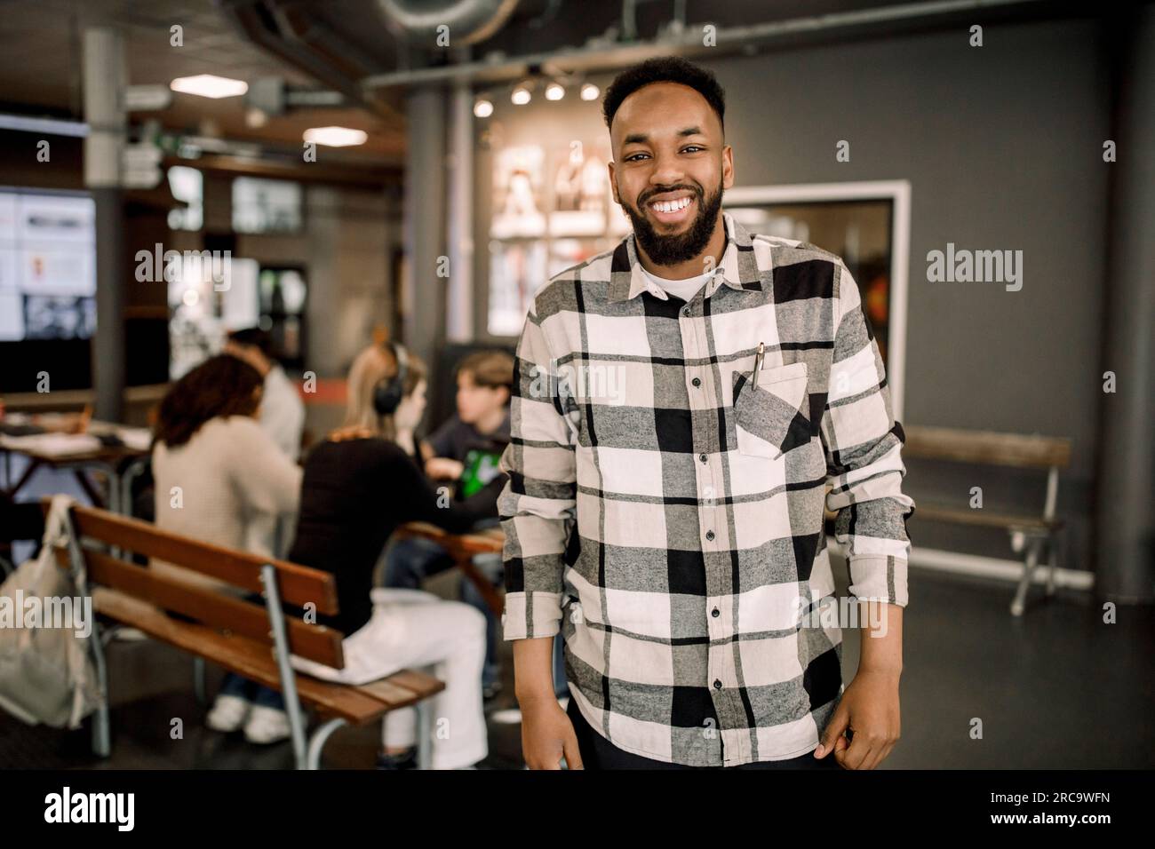 Portrait of happy male teacher wearing plaid shirt while standing in high school Stock Photo