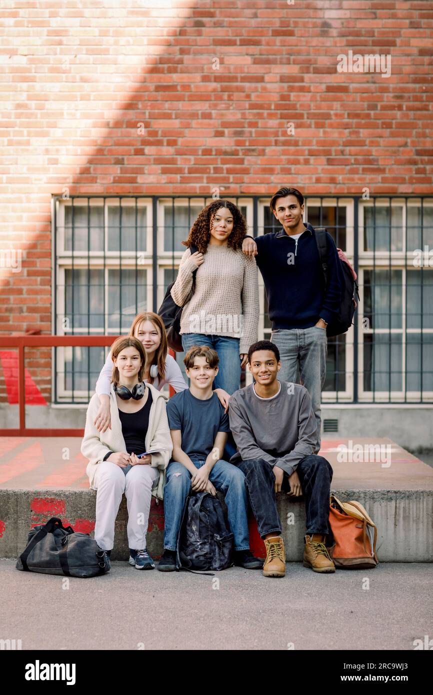 Portrait of smiling male and female students in high school campus ...