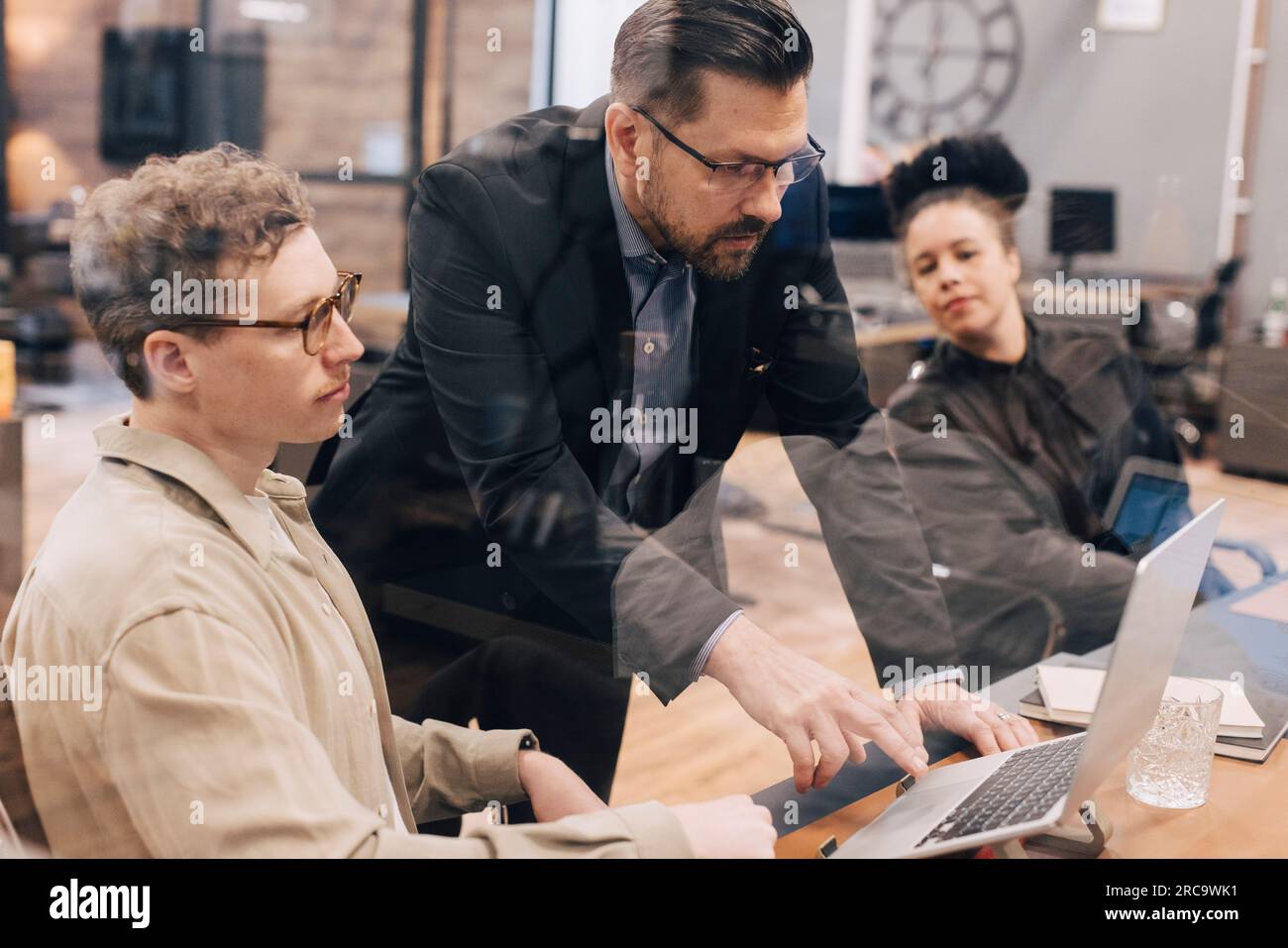Manager using laptop while discussing with businessman in office Stock Photo