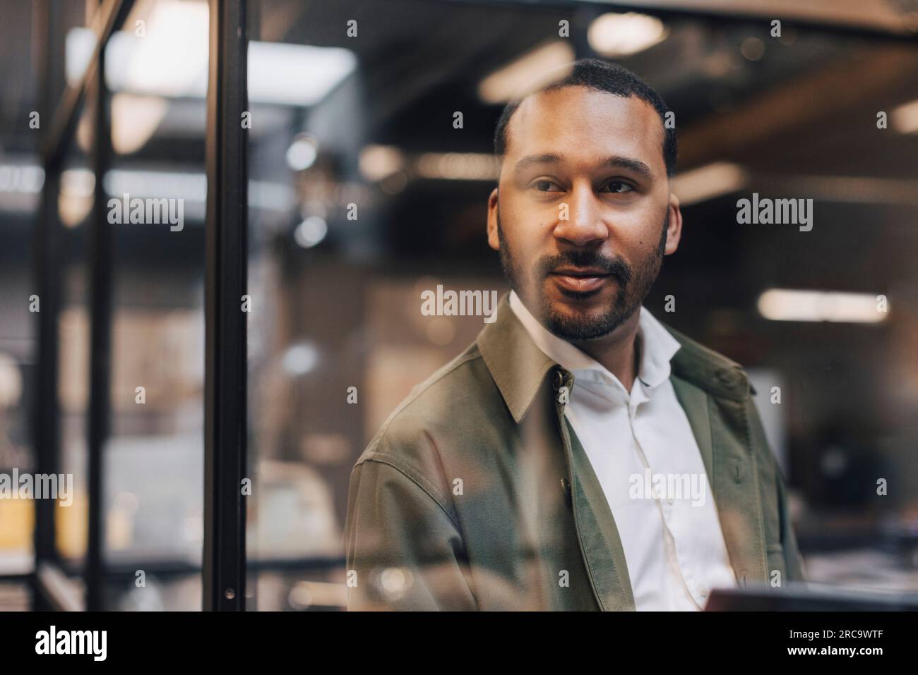 Thoughtful businessman standing in illuminated office Stock Photo