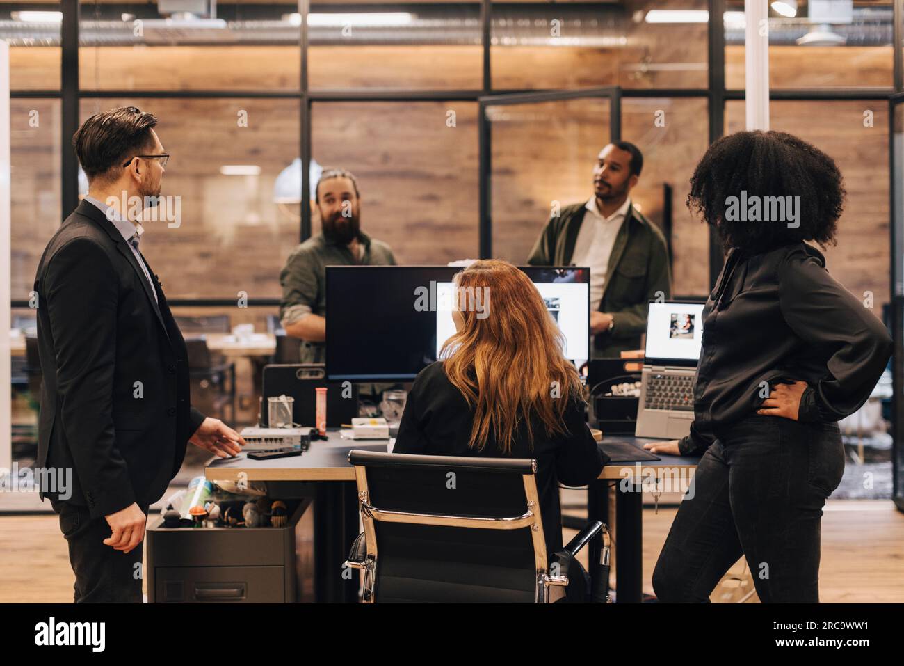 Colleagues and manager discussing over computer in office Stock Photo