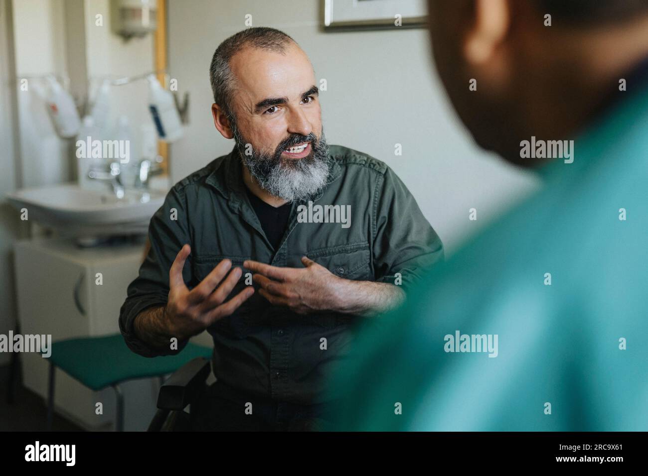 Mature patient gesturing while explaining doctor in clinic Stock Photo