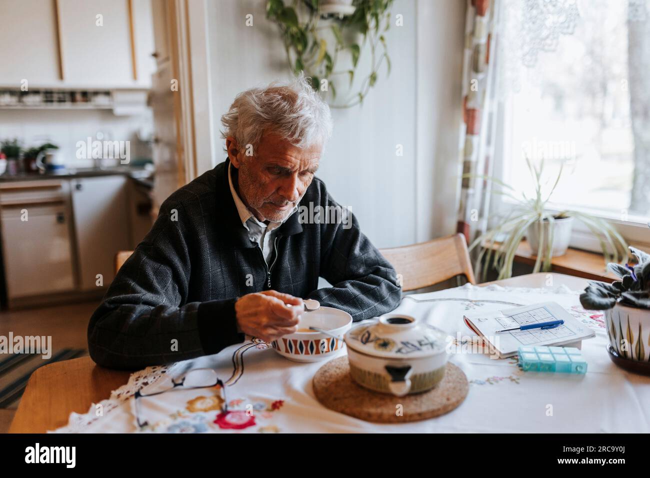 Senior man eating breakfast while sitting at dining table in home Stock Photo