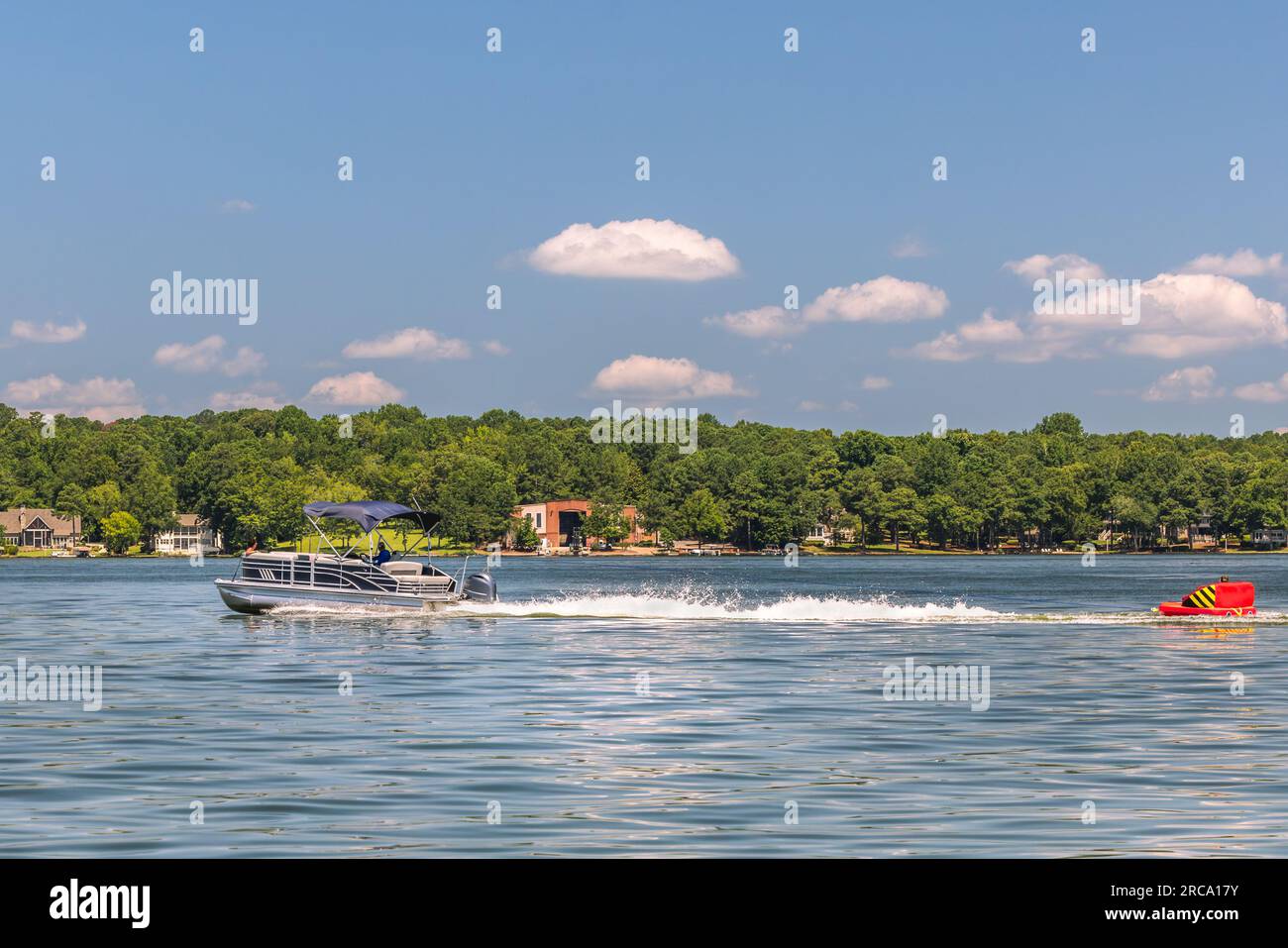 Pontoon boat pulling inflatable tube float raft on lake. Family on a ...