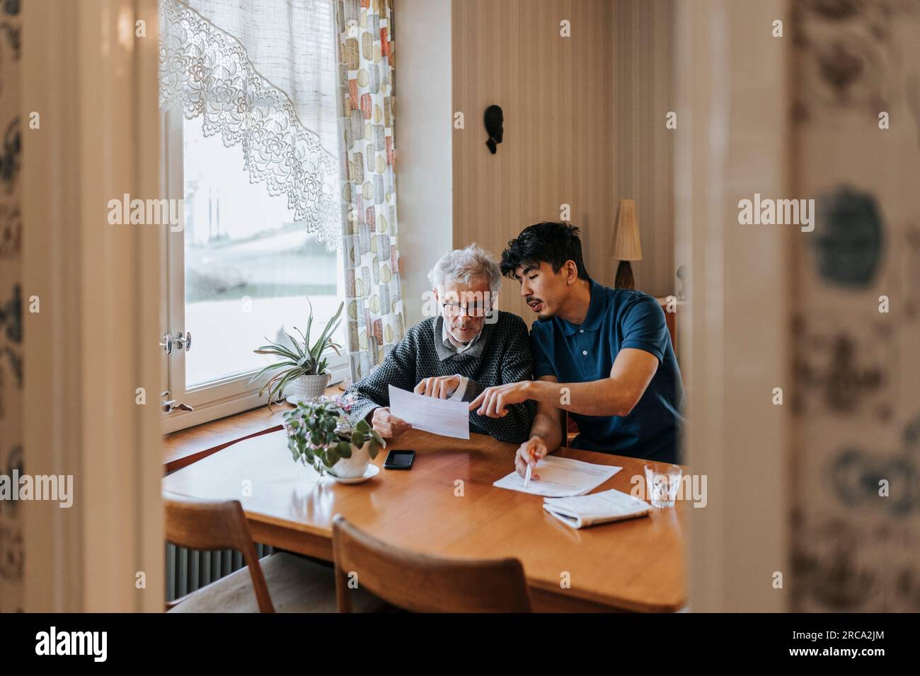 Male caregiver explaining medical reports to senior man at home Stock Photo