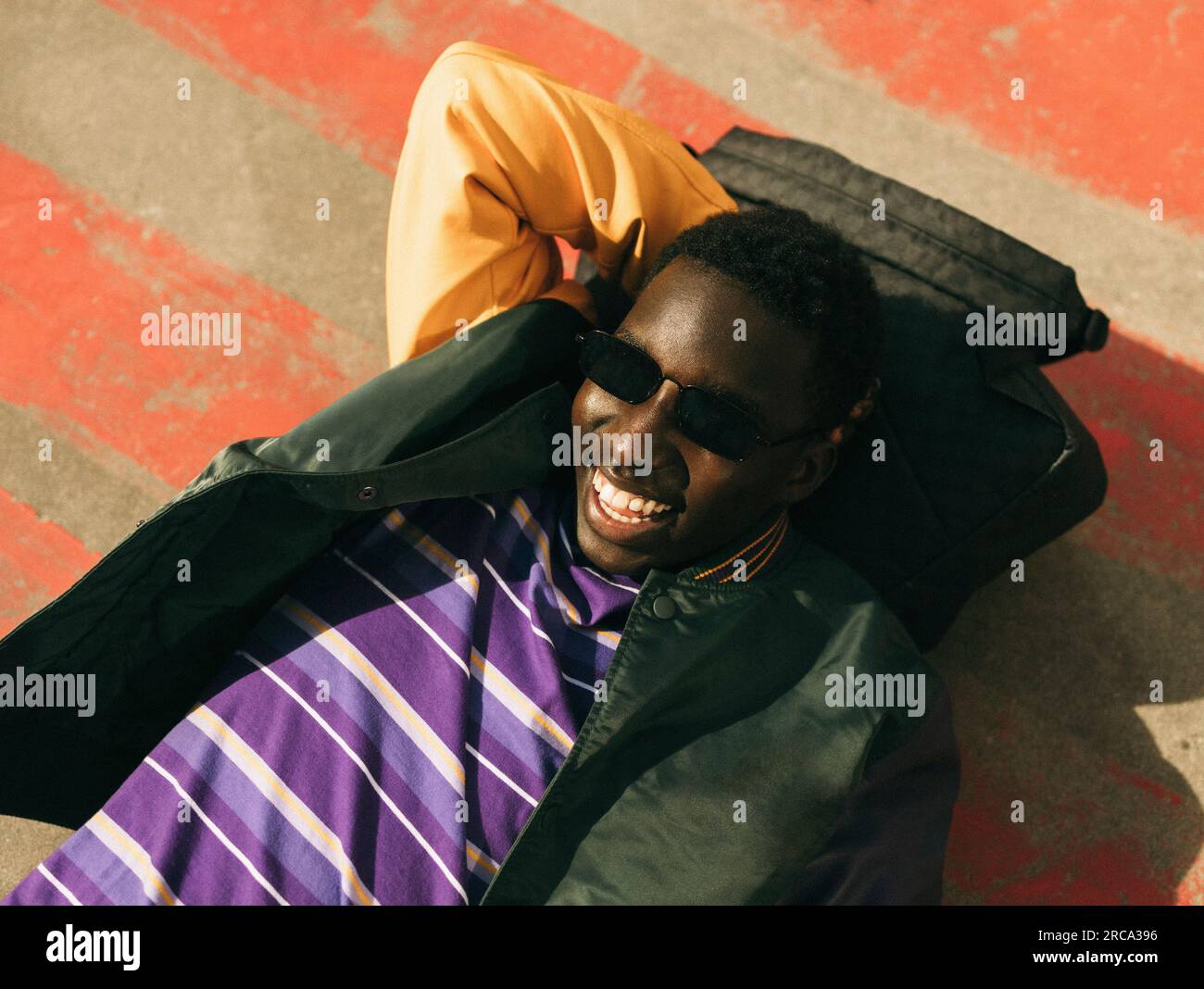 Carefree young man wearing sunglasses while lying on floor during sunny day Stock Photo
