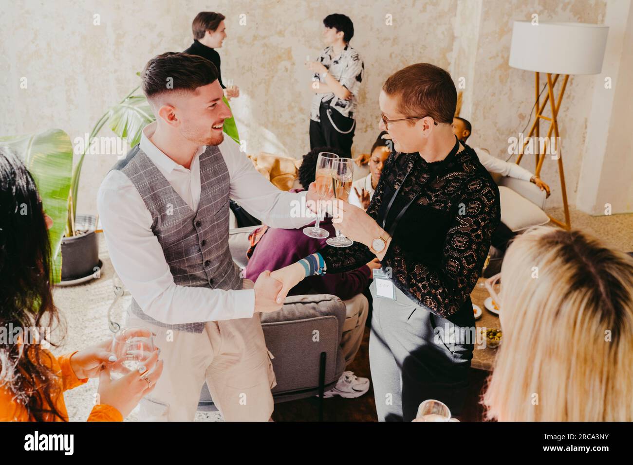 Smiling business colleagues toasting wineglass and shaking hands during event at convention center Stock Photo