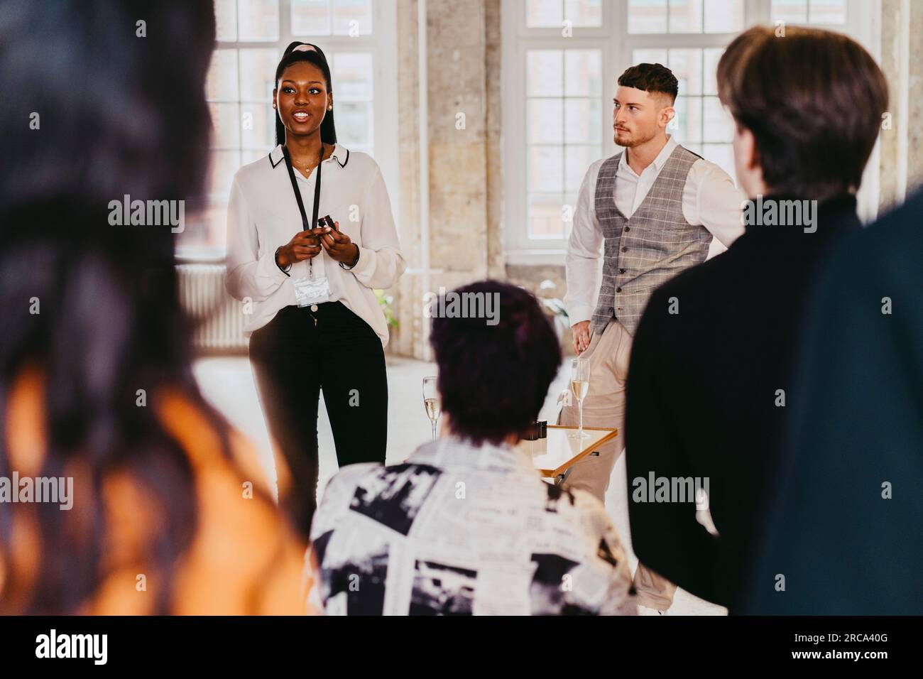Smiling businesswoman giving speech to colleagues during product launch event at convention