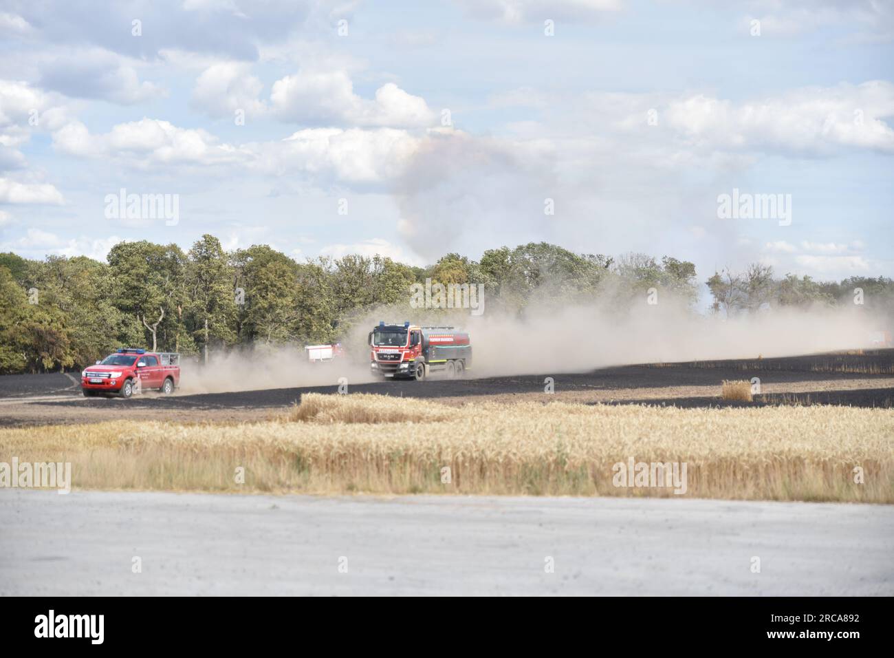 Eulau, Germany. 13th July, 2023. Vehicles of the fire department drive along a burned field near Eulau. A fire broke out between the towns of Markröhlitz and Eulau in the Burgenland district on Thursday afternoon. Credit: Thomas Dilthey/dpa/Alamy Live News Stock Photo