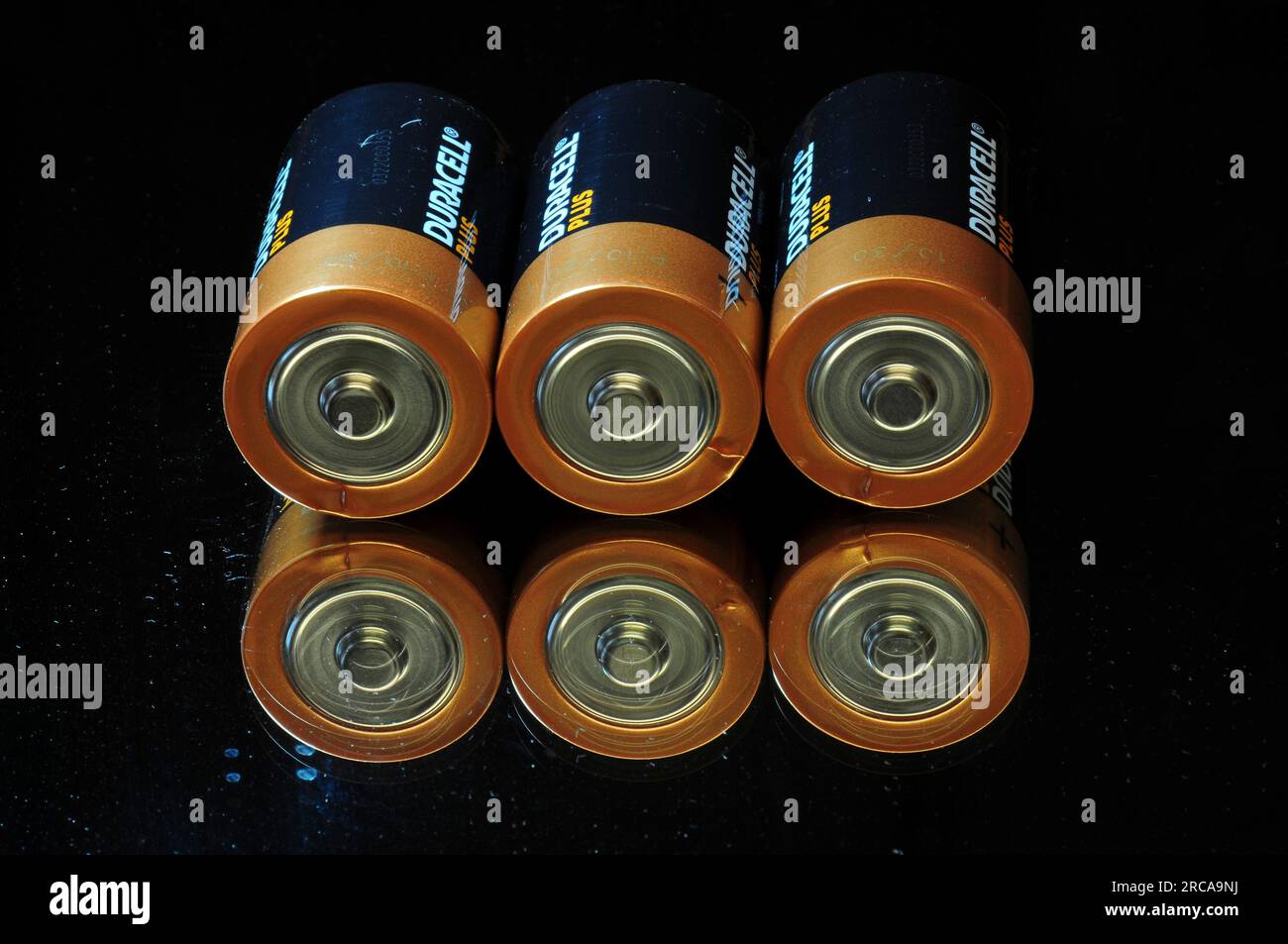 Three Duracell plus alkaline batteries standing on mirror surface Stock