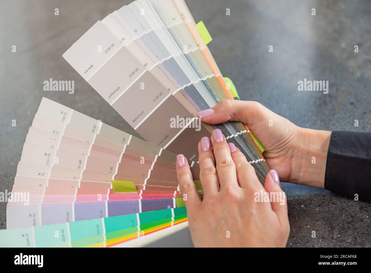 Color selection according to RAL. A woman designer chooses a shade from the RAL color palette. The concept of design work and color selection in the Stock Photo