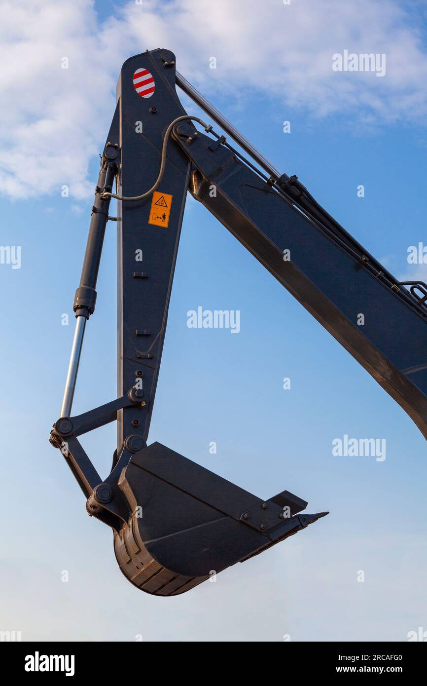 Lifting boom and bucket of a black excavator against the sky Stock
