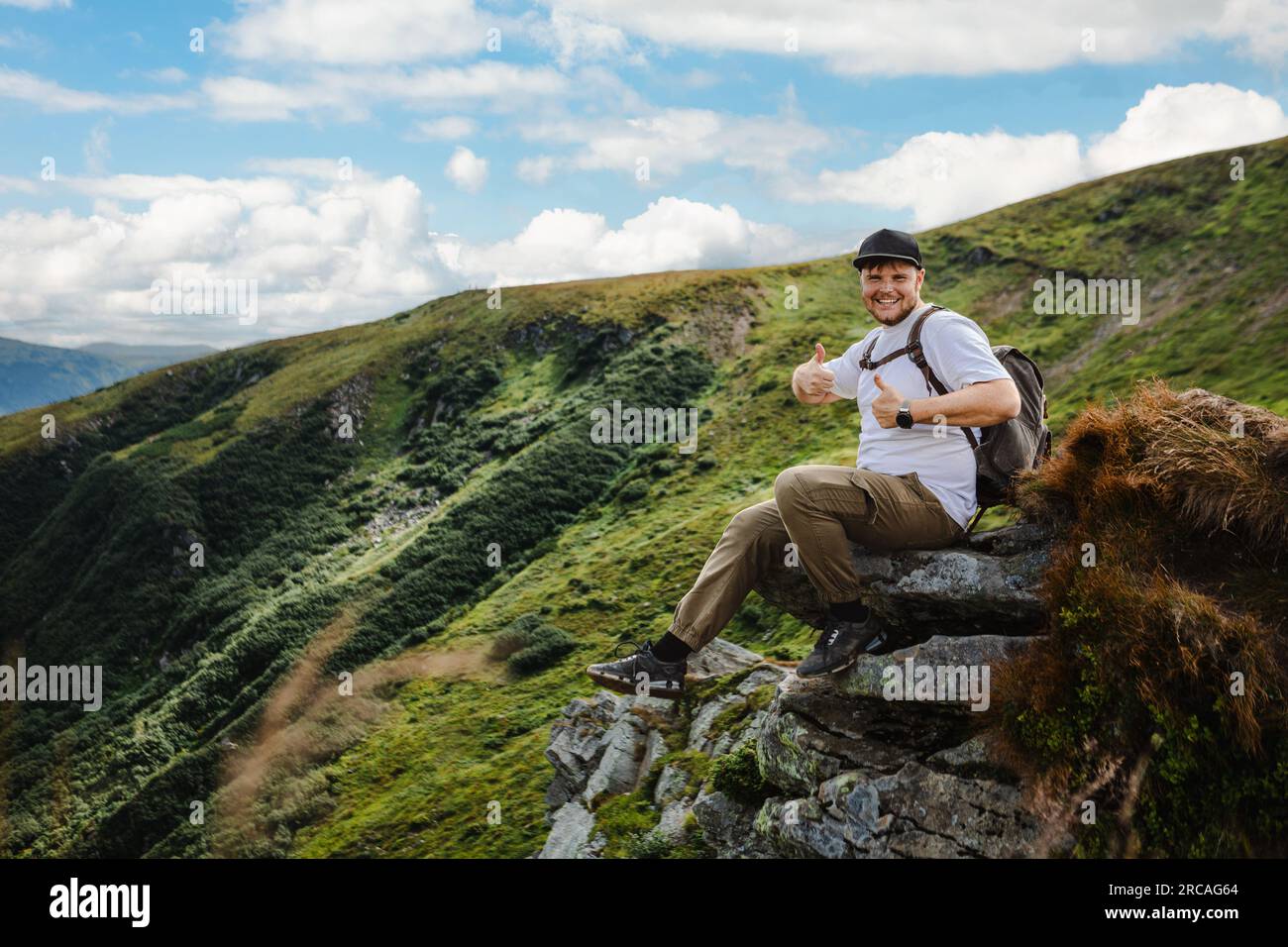 Man on top of a mountain sitting on a rock Stock Photo - Alamy