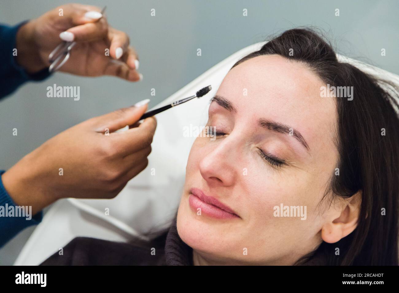 Caucasian woman removing hair from eyebrows with thread technique done