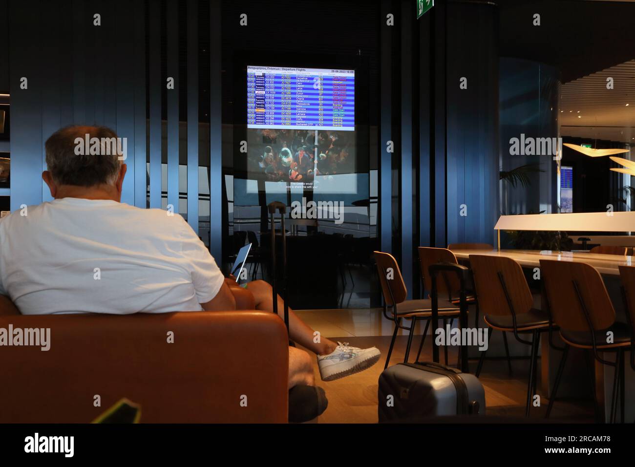 Athens Greece Athens International Airport (AIA) Eleftherios Venizelos Man Waiting in Executive Lounge Electronic Departures Board Stock Photo