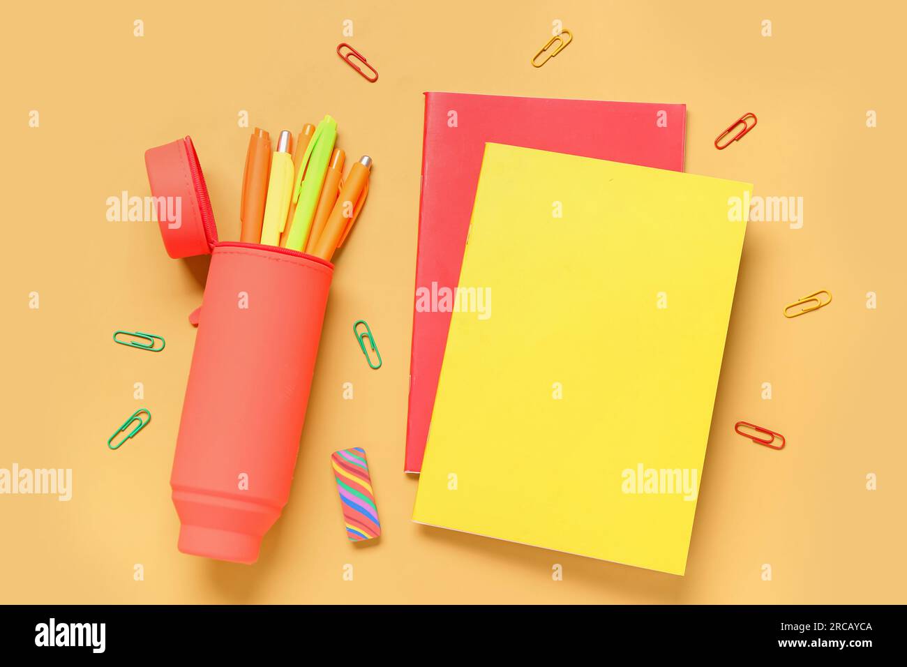 Case with pens and notebooks on orange background Stock Photo