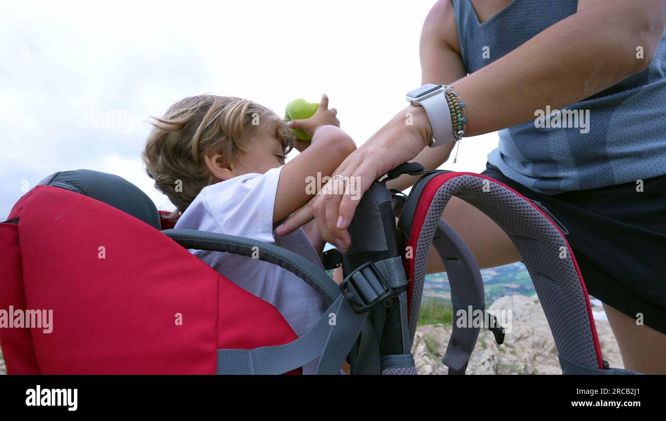 Mother lifting child from inside carrying hiking backpack Stock Photo