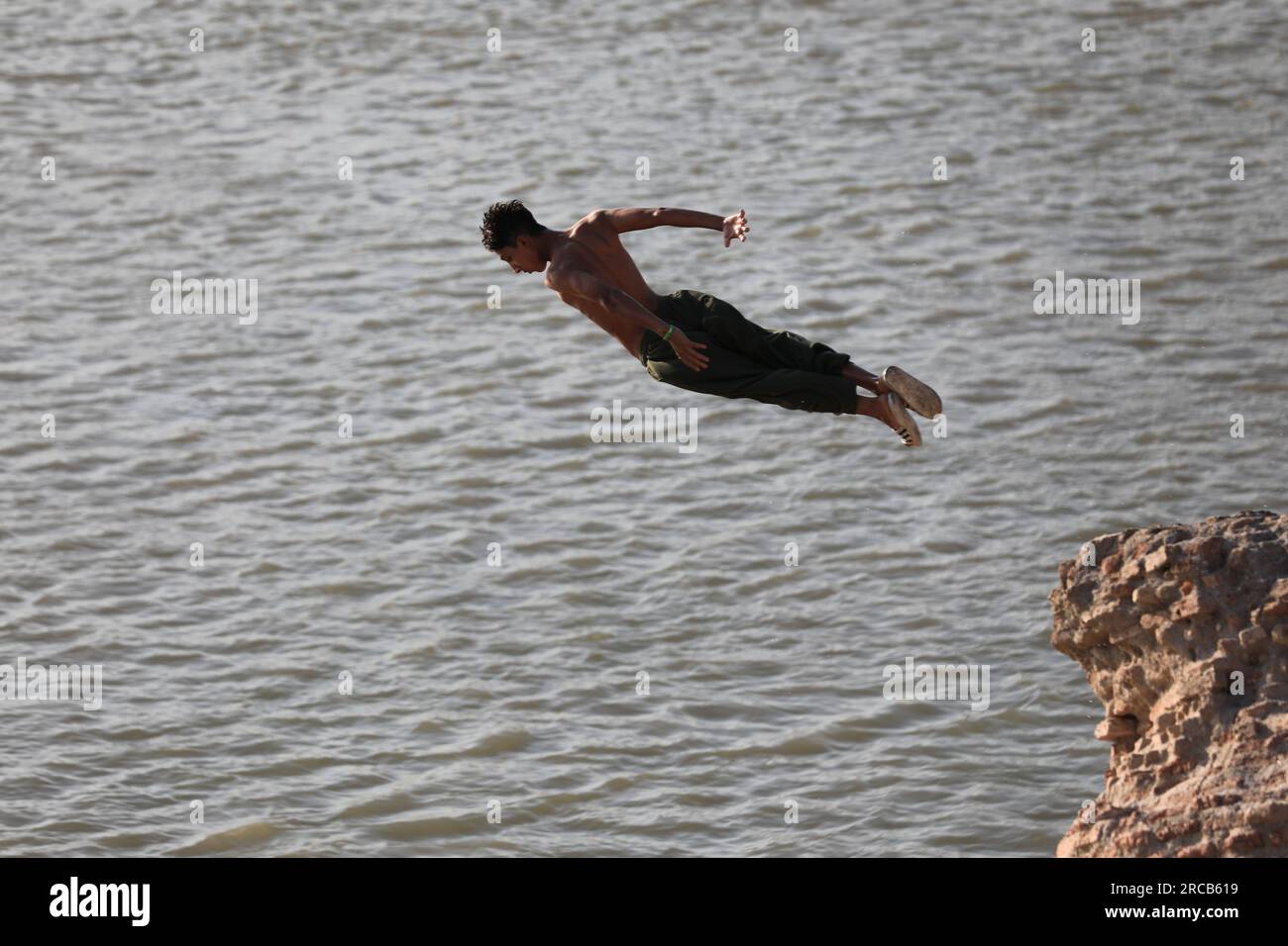 Baghdad, Iraq. 13th July, 2023. An Iraqi man dives into the water of