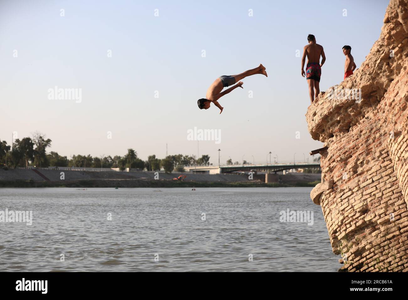 Baghdad, Iraq. 13th July, 2023. An Iraqi man dives into the water of