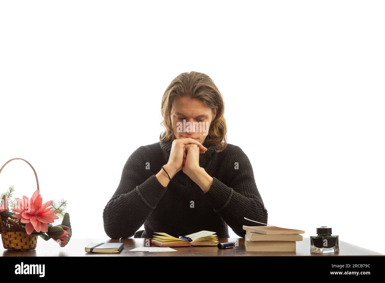 A young student sits at a table and thinks. Stock Photo