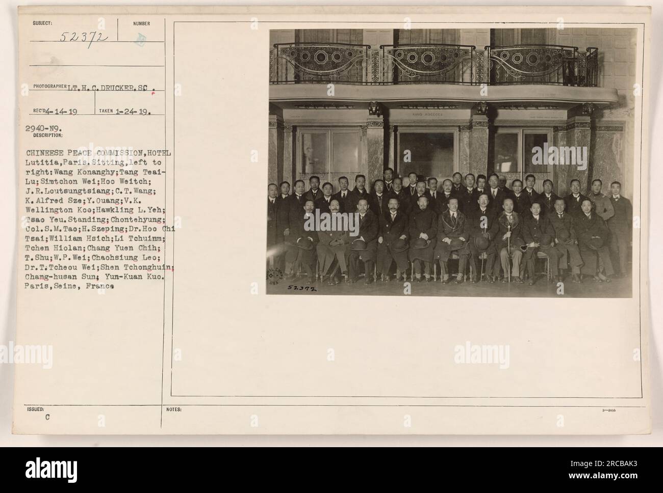 Chinese Peace Commission, Hotel Lutitia, Paris. Photograph taken on January 24, 1919, by photographer TT.H.C. Drucker. Caption describes the individuals in the photograph, including their names and positions. The photograph shows a group of Chinese delegates seated and standing together in a hotel room in Paris, France during World War I. Stock Photo