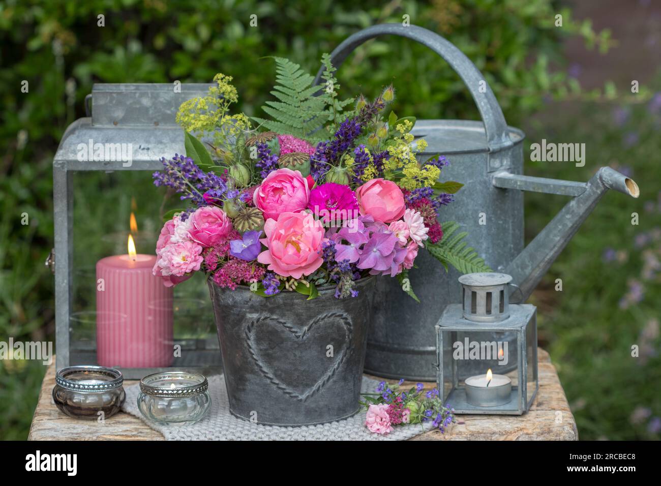 vintage arrangement with bouquet of pink roses and summer flowers in zinc pot and lanterns Stock Photo