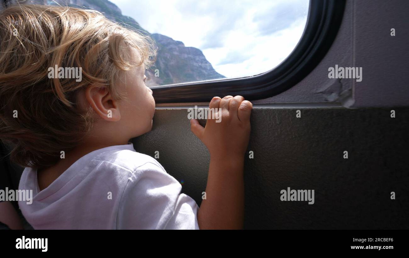 Child inside teleferic transportation looking out window traveling during vacations Stock Photo