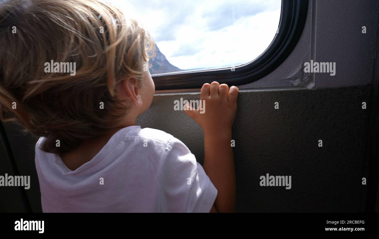 Child inside teleferic transportation looking out window traveling during vacations Stock Photo