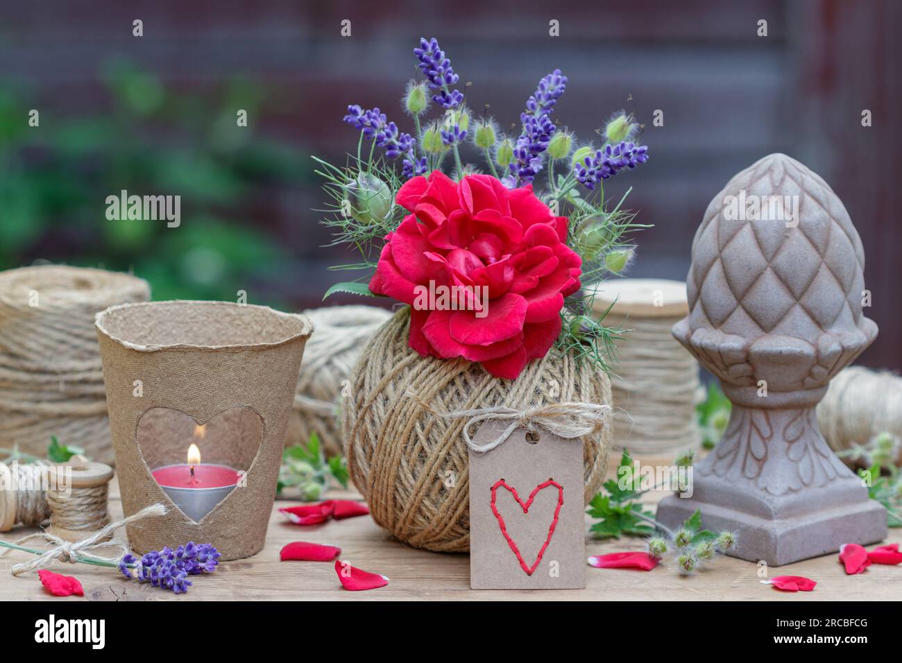romantic decoration with bouquet of red rose and lavender flowers, table lantern and balls of yarn Stock Photo