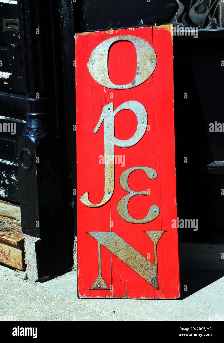 Rustic, red sign is wooden and cracked from exposure. Metal letters are ...