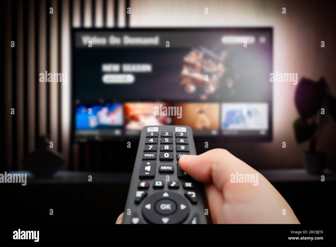 VOD service screen. Man watching TV with remote control in hand. Stock Photo