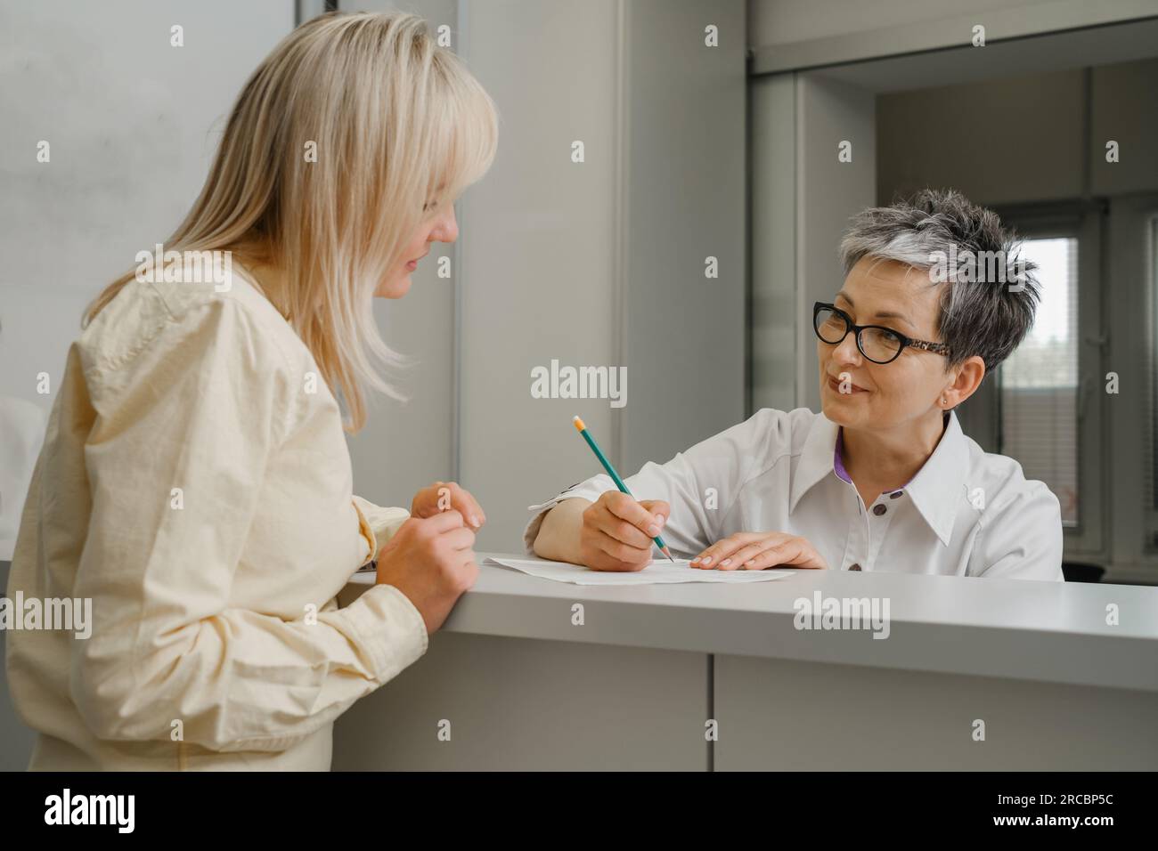 Patient at reception desk of clinic talking about her appointment