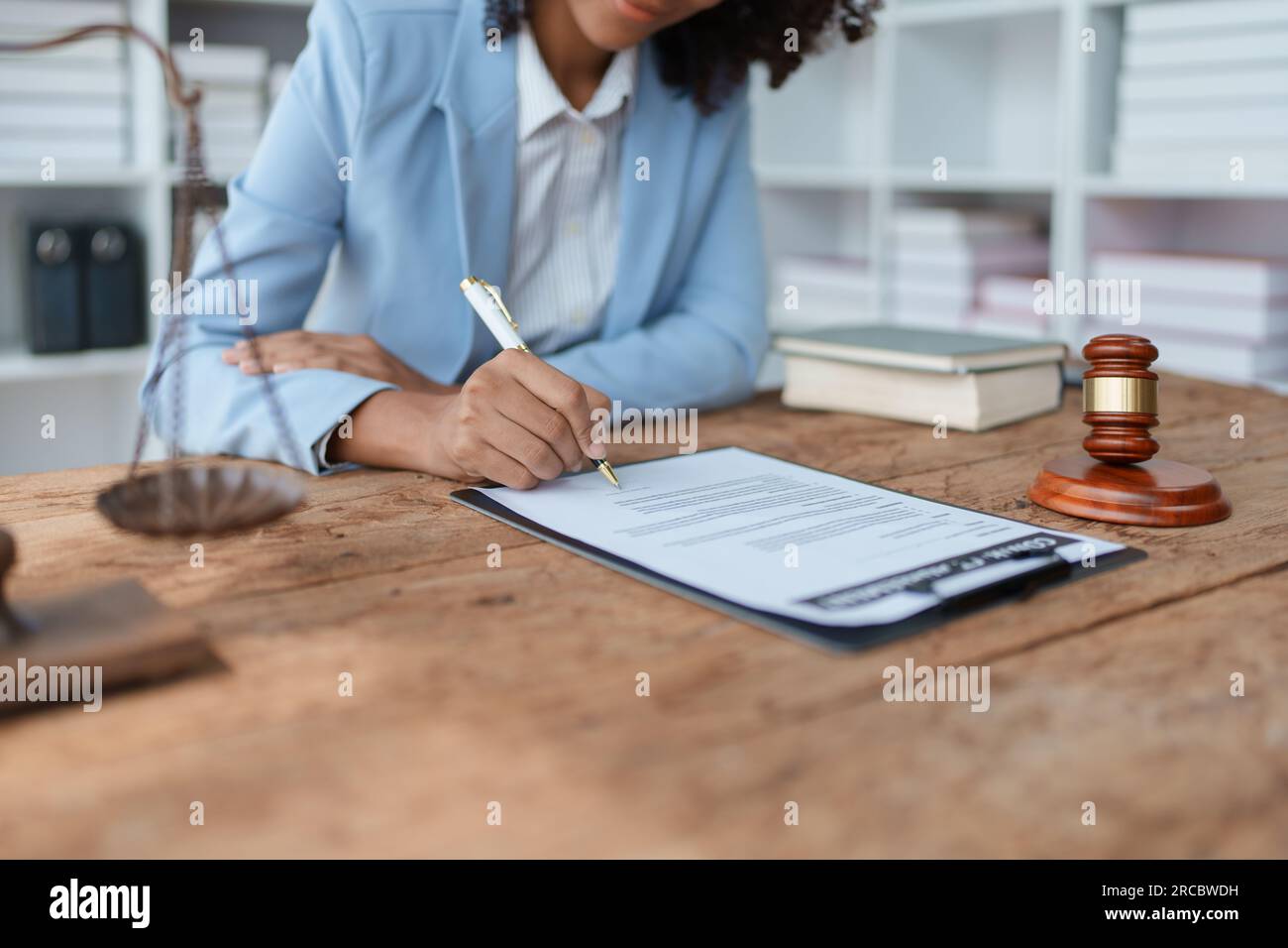 Young African American lawyer studying a case for a client and signing a legal contract to fight her opponent in court. Legal and lawyer concepts. Stock Photo