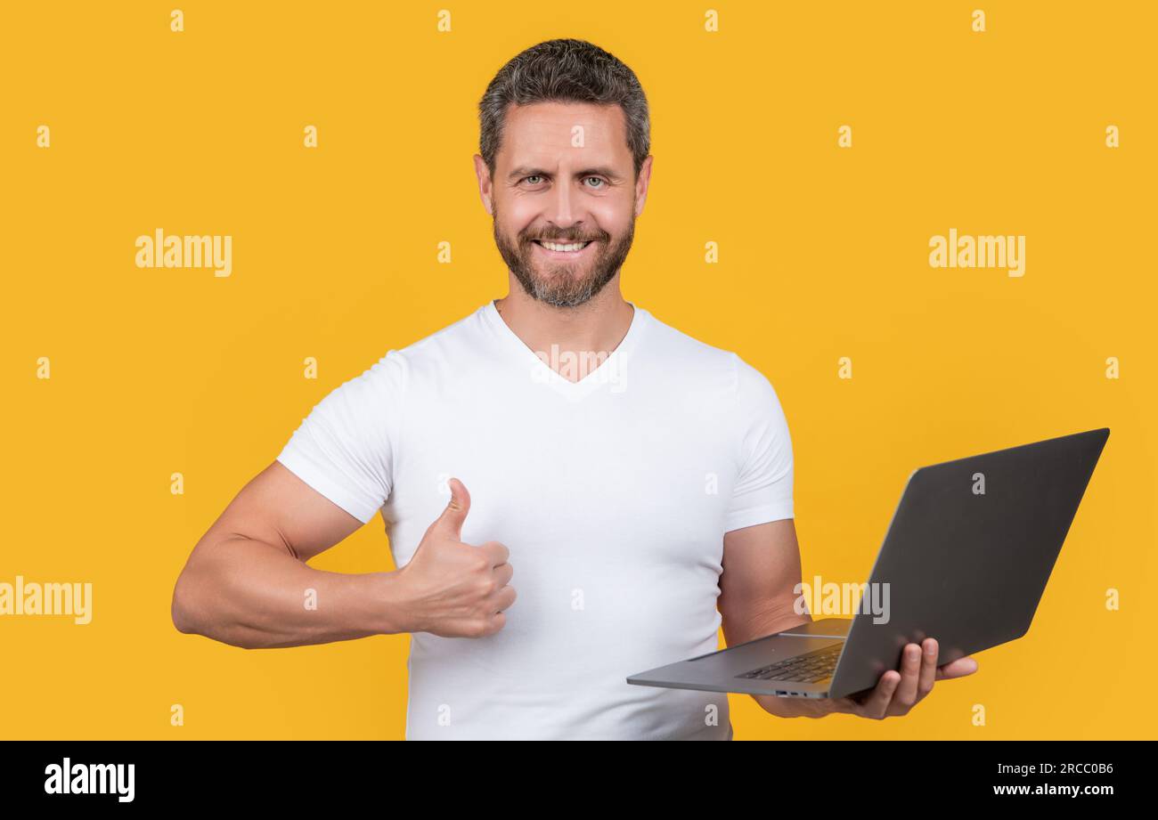 man programmer with laptop show thumb up isolated on yellow background ...