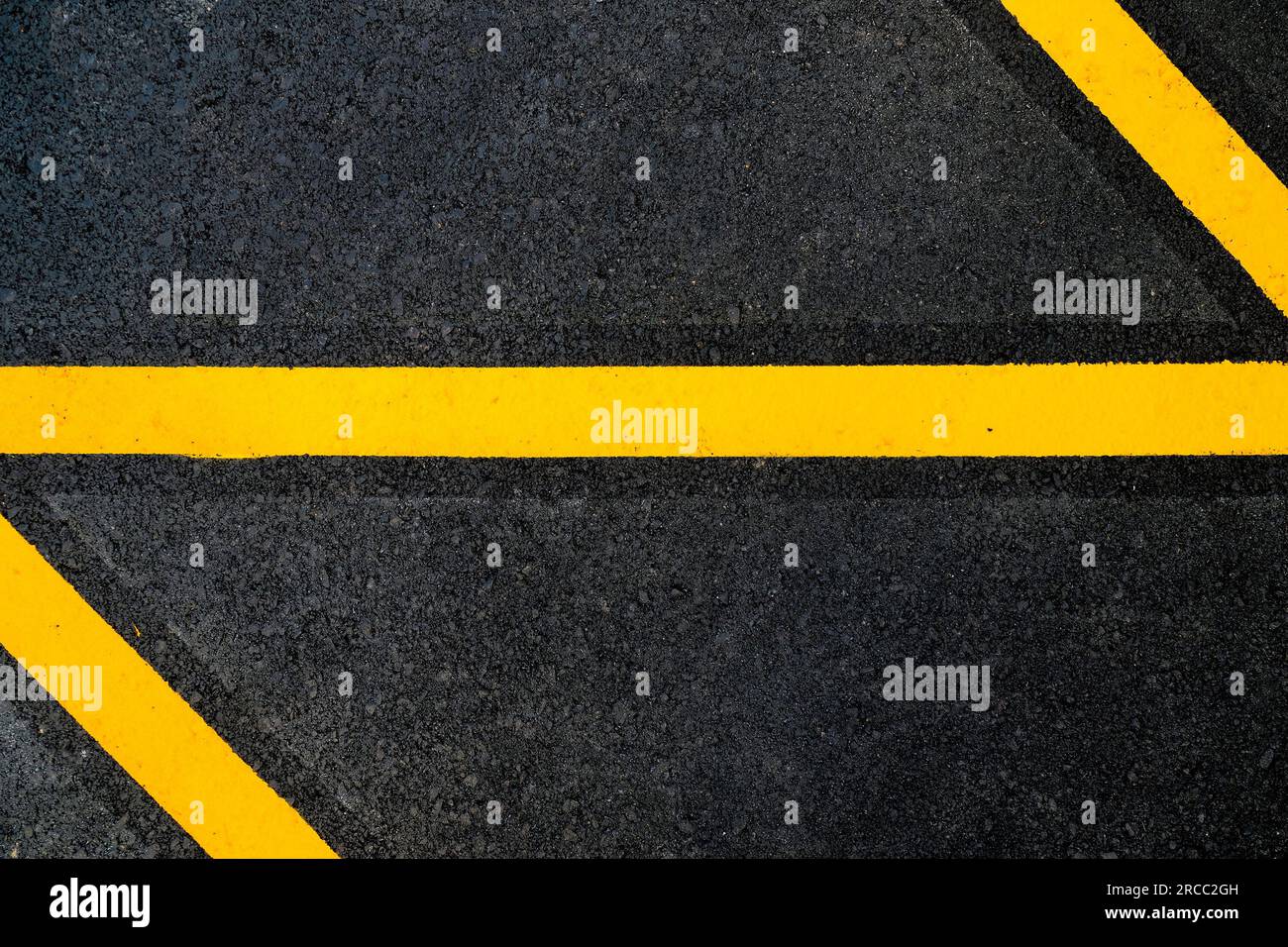 Abstract fragment of yellow markings painted on black tarmac road Stock