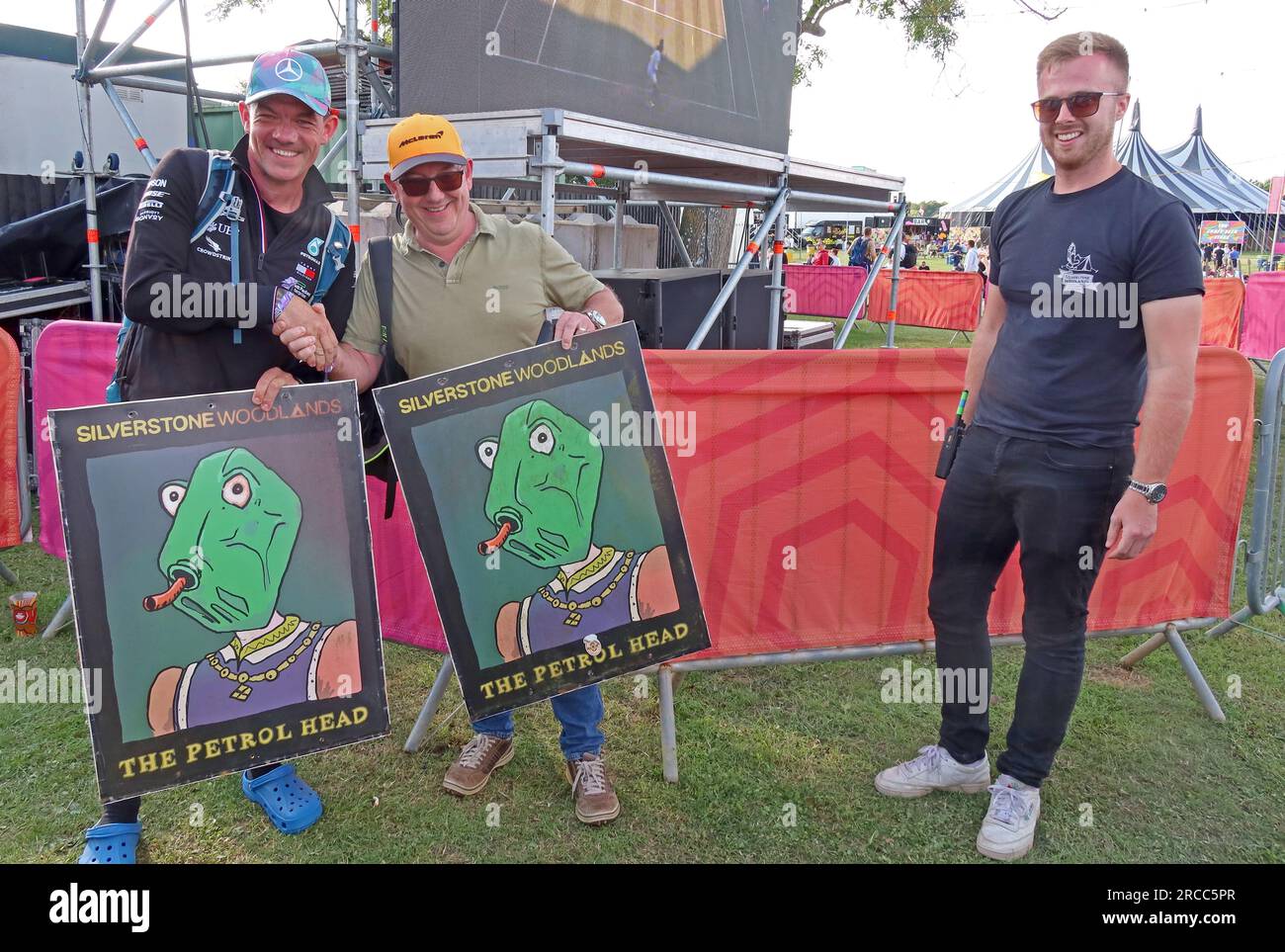 Winners of a charity auction pose with illustrated pub signs from The Petrol Head pop-up pub at Silverstone Woodlands camping during the F1 GP 2023 Stock Photo