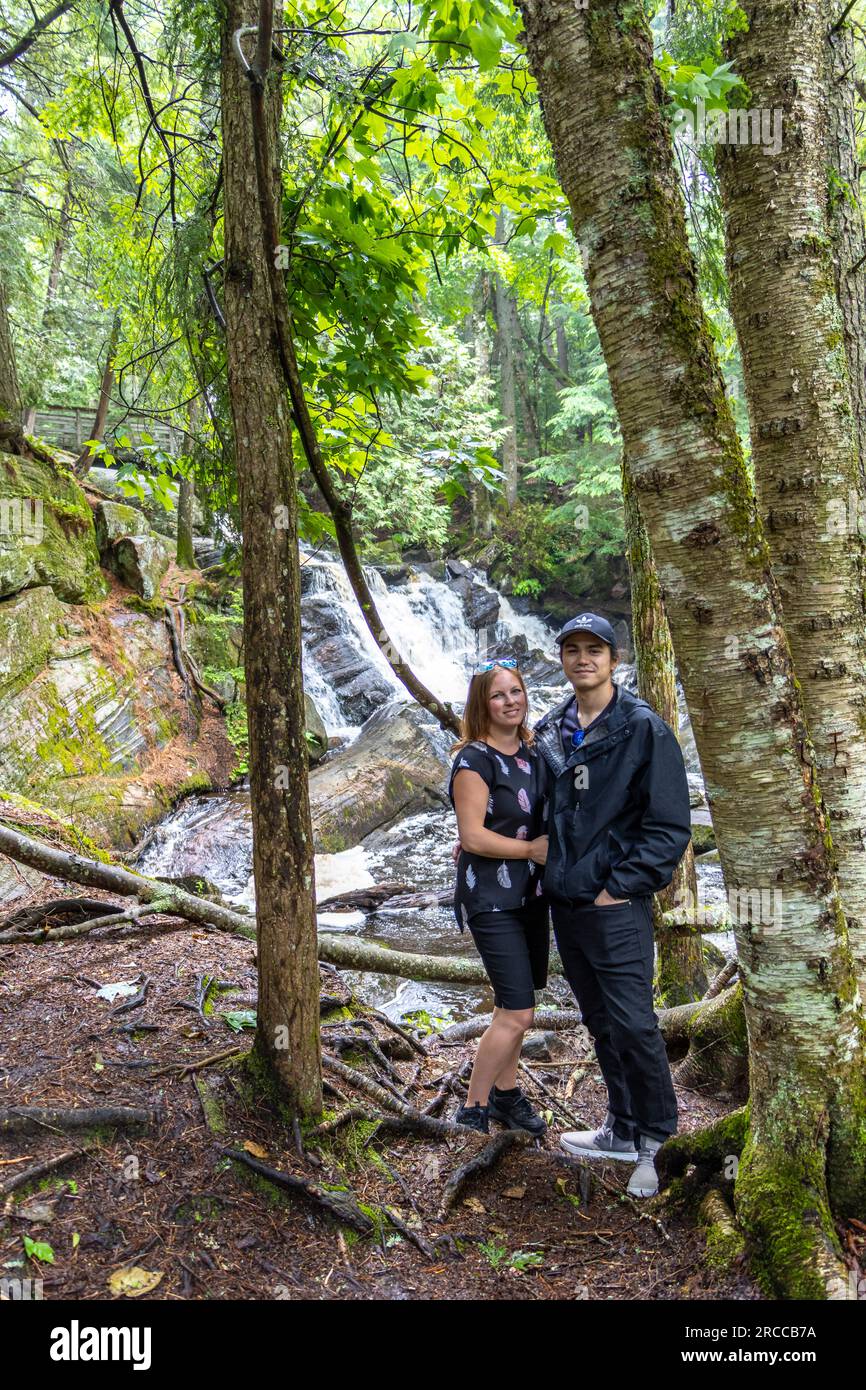 couple posing in front of waterfall in thick forest Stock Photo