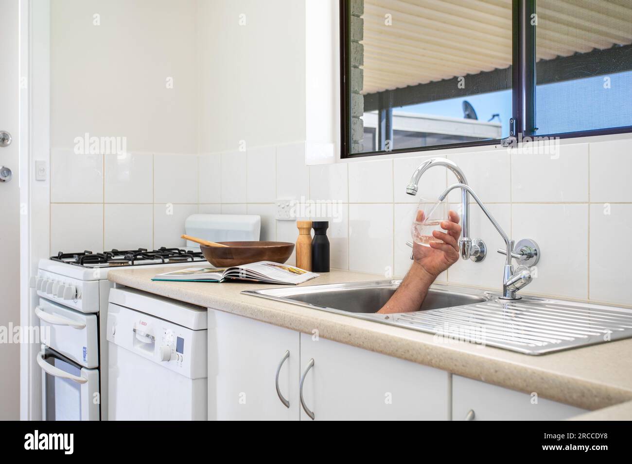 Hand coming out of sink filling glass with water Stock Photo Alamy