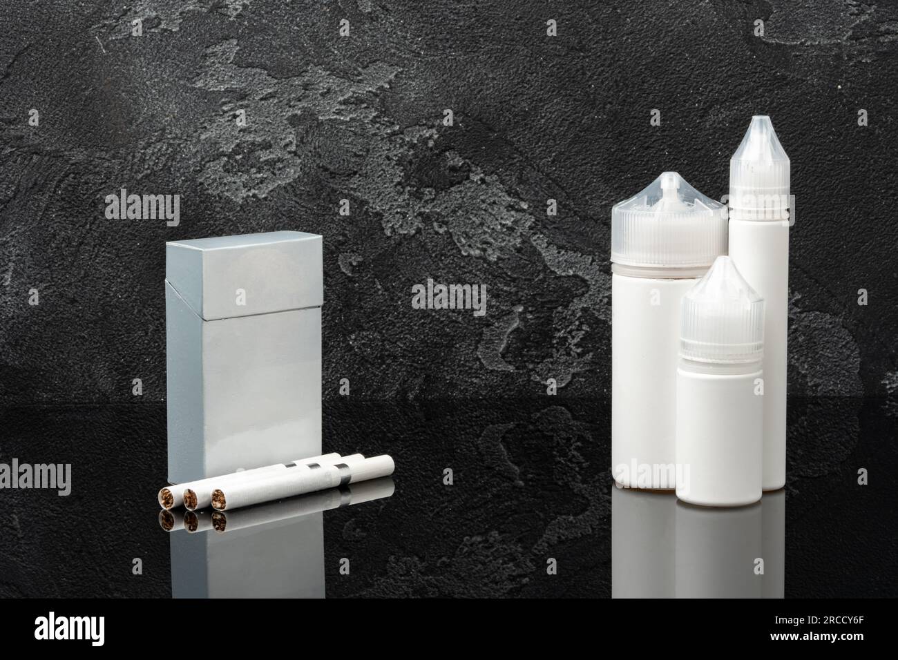 Pack of cigarettes and e-juice liquid bottles on black background Stock Photo