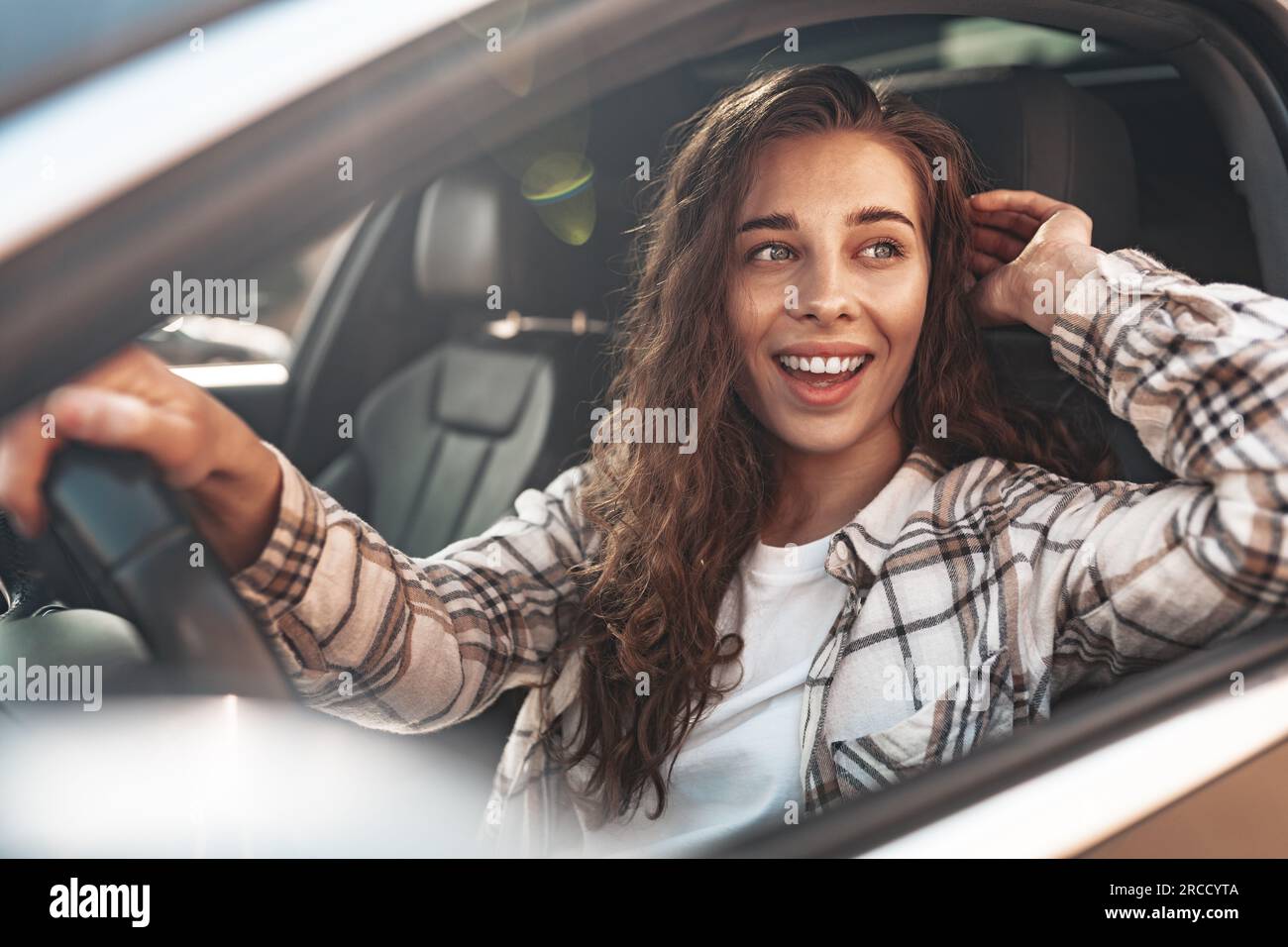 Portrait of a beautiful smiling woman in a car looking out of the ...