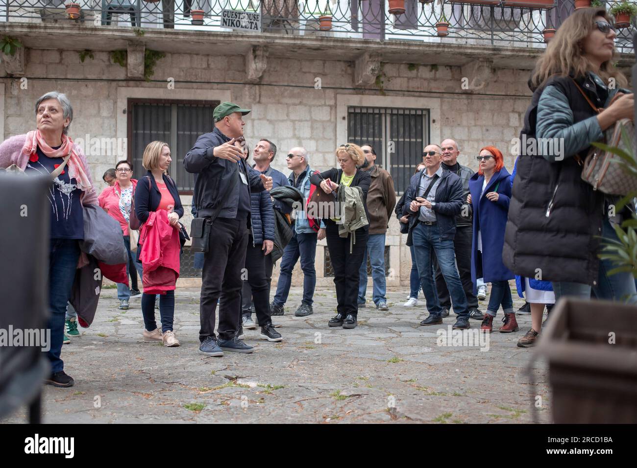 Kotor, Montenegro, Apr 13, 2023: A large group of tourists gathered around guide at Cinema Square in Old Town Stock Photo