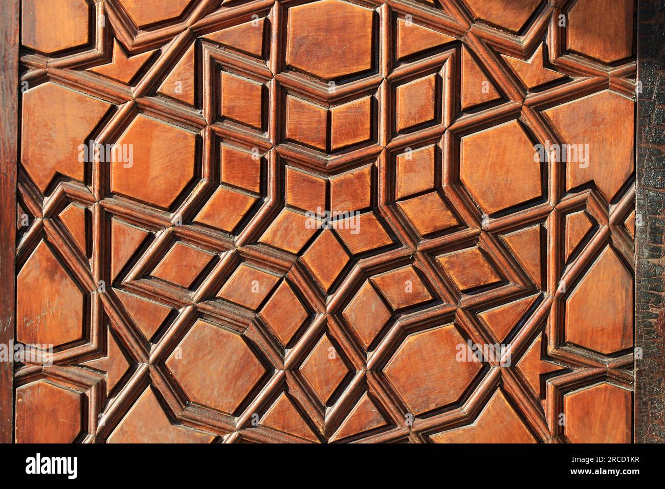 An old handcrafted wooden door. No nails were used in the construction of the door. There are geometric motifs on the door. Stock Photo