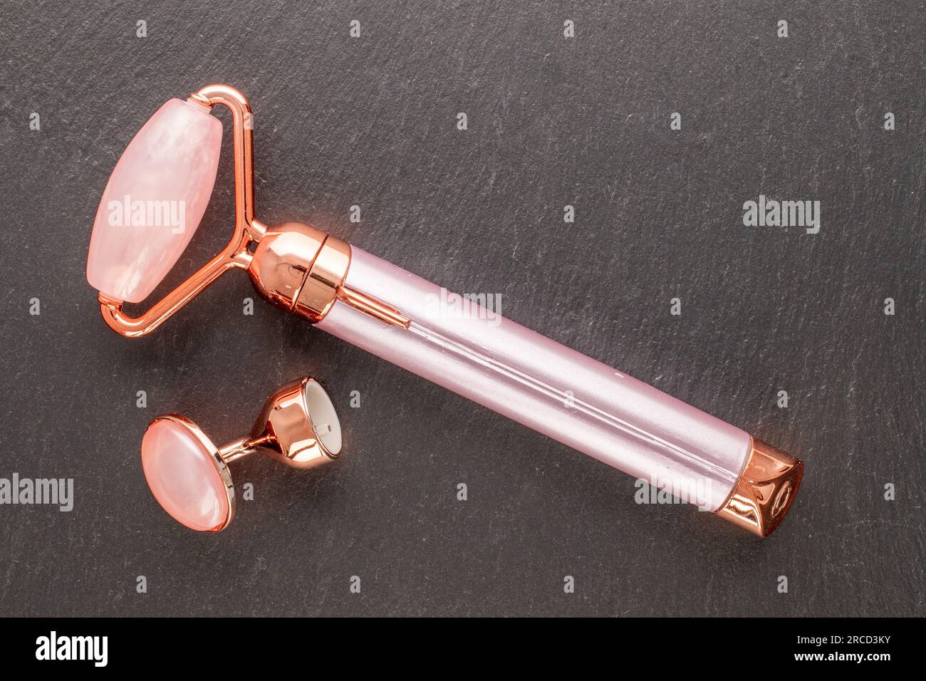 Facial roller, device handle with AA batteries, eye stone on slate
